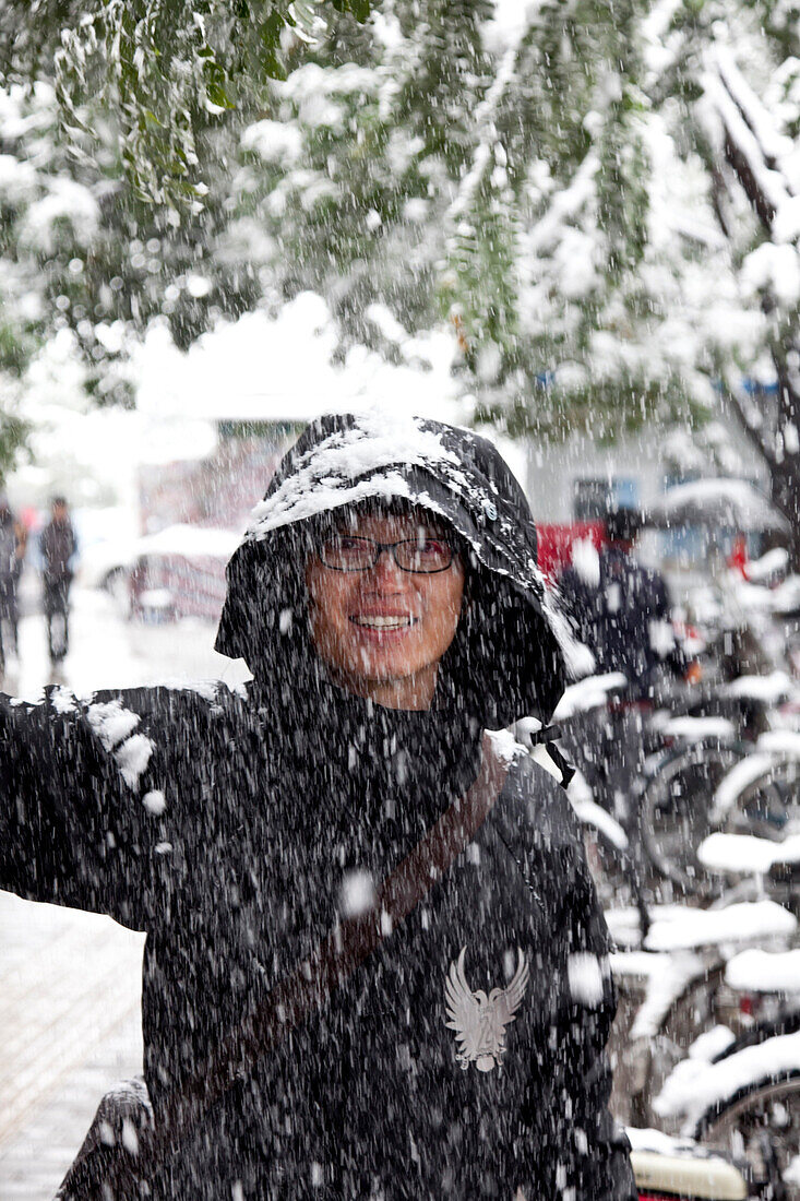 Verschneites Peking, Strassenszene, lachender Mann, Schnee vom Baum, Schnee ist selten in Peking, VR China