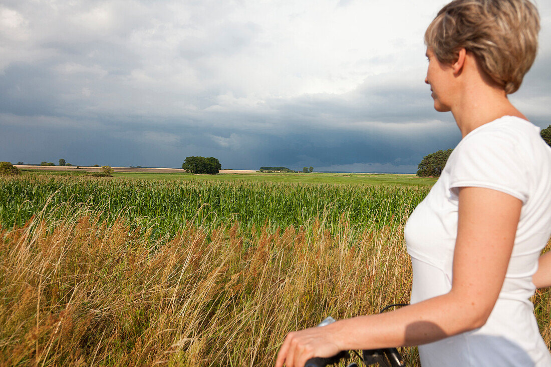 Frau blickt auf ein Maisfeld, Stolpe, Insel Usedom, Mecklenburg-Vorpommern, Deutschland