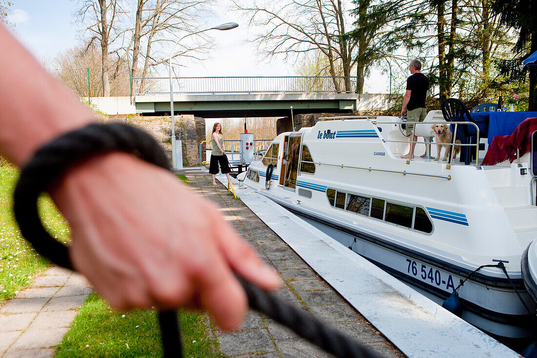 Hand hält Seil während ein Le Boat Hausboot durch Schleuse manövriert, nahe Zechlinerhütte, Nördliche Brandenburgische Seenplatte (nahe Mecklenburgische Seenplatte), Brandenburg, Deutschland, Europa
