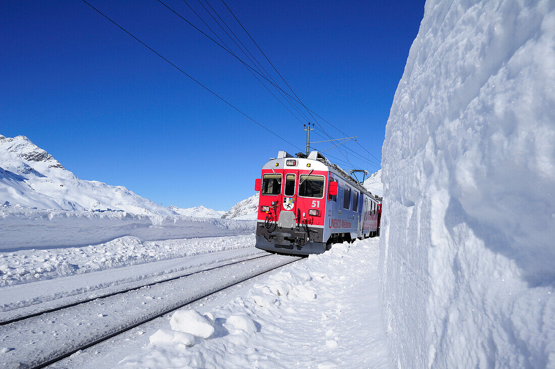 Zug der Rhätische Bahn fährt durch Winterlandschaft zum Berninapass, UNESCO Weltkulturerbe Rhätische Bahn, Rhätische Bahn, Albula-Bernina-Linie, Berninabahn, Berninagruppe, Oberengadin, Engadin, Graubünden, Schweiz, Europa