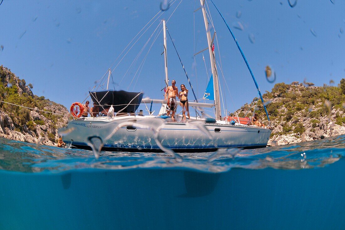 Mediterranean Sea off the Turkish coast a man and a woman in their 20s standing on the deck of a yacht as seen from underwater