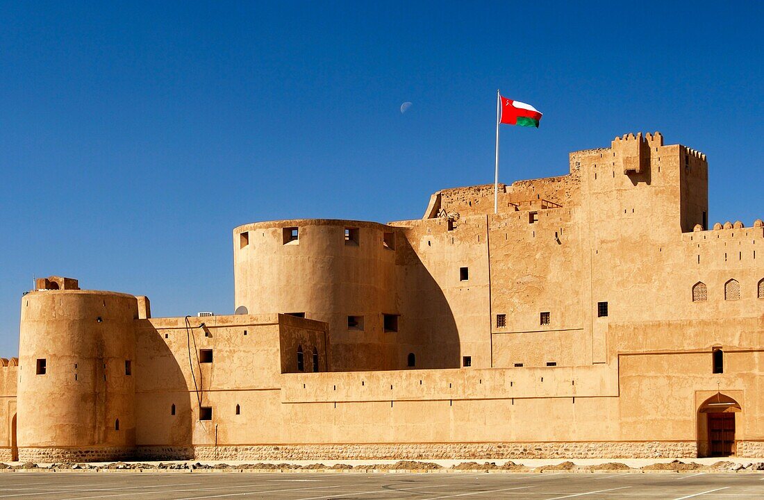 National flag of Oman fluttering over the Jabrin castle, historic adobe fort in the Dhakiliya Region, Sultanate of Oman
