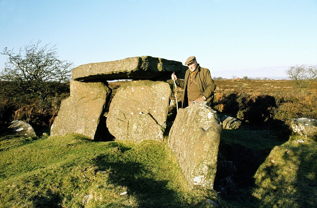 Old man beside prehistoric Neolithic burial chamber dolmen known as Craig's Tomb near Ballymoney, Co Antrim, Northern Ireland