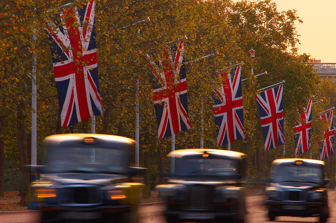 Black cabs driving along The Mall at dusk, London, UK - England