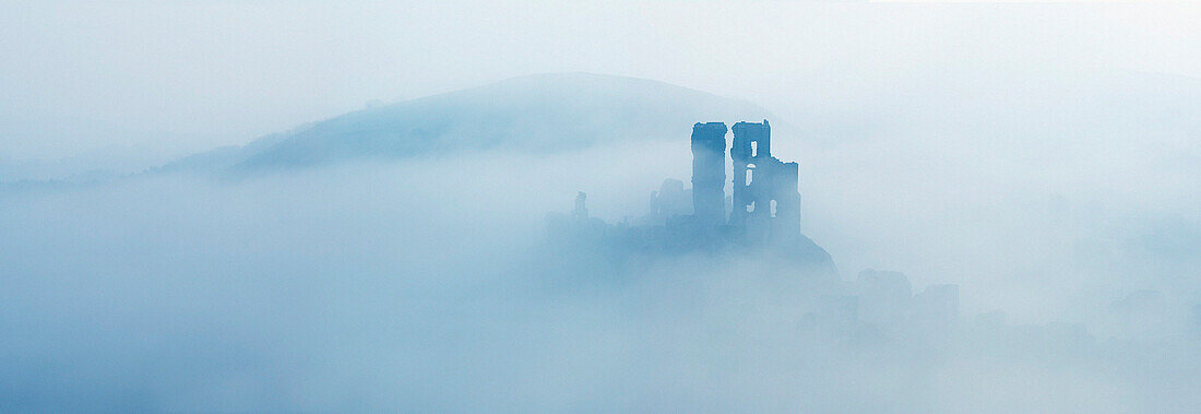 Corfe Castle and the Purbeck Hills in mist at dawn, Corfe, Dorset, UK - England