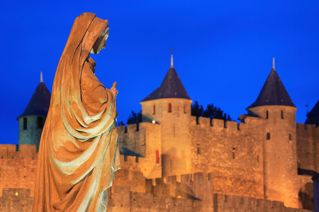 Walled city and statue at night, Carcassonne, Languedoc-Roussillon, France