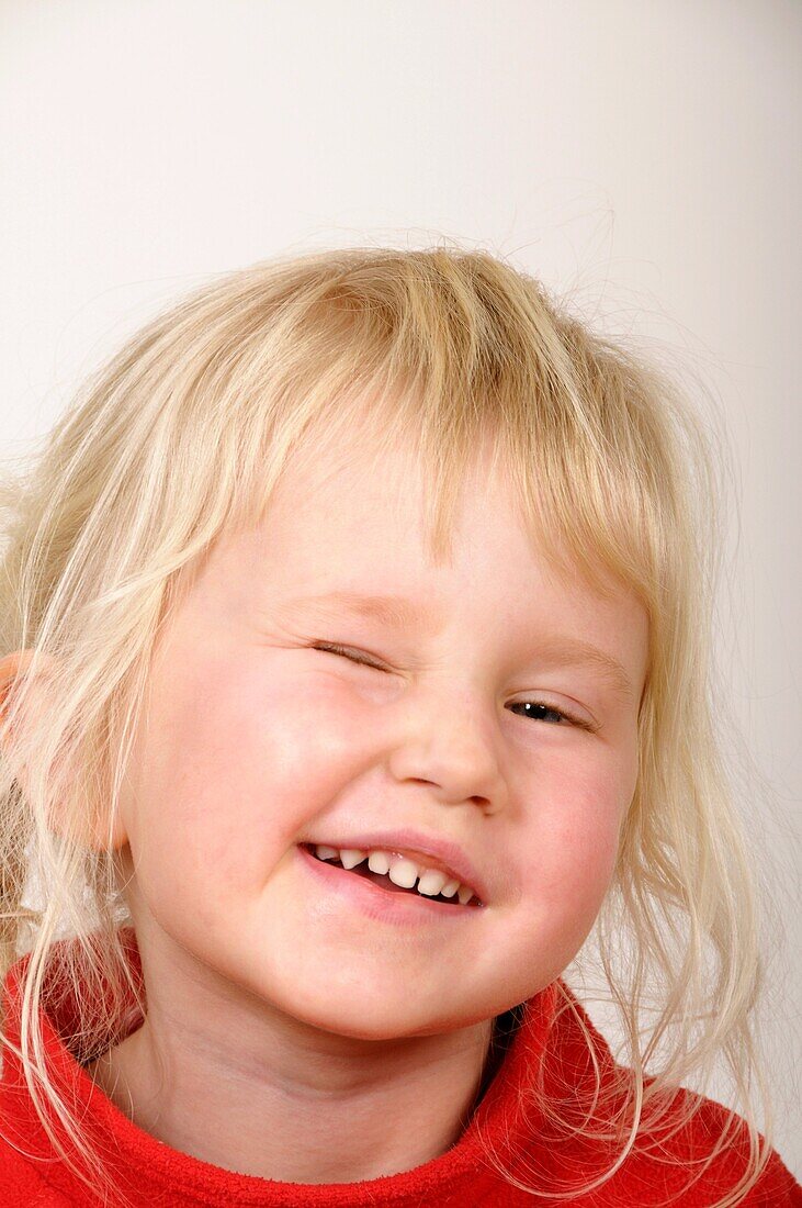 Stock photo of a portrait of a four year old girl looking at the camera and winking
