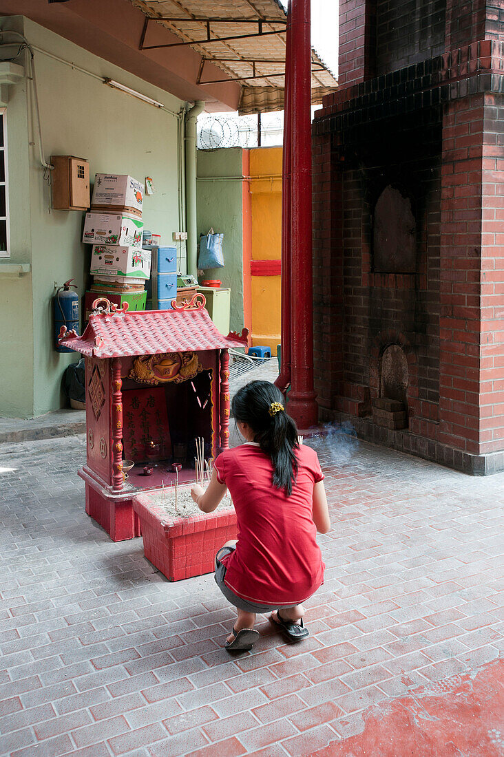 Junge Frau setzt Räucherstäbchen in einem chinesischen Tempel, Kuala Lumpur, Malaysia, Asien