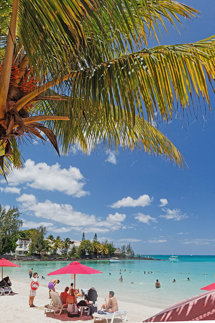 Palm trees and people on the beach in the sunlight, Pereybere, Mauritius, Africa