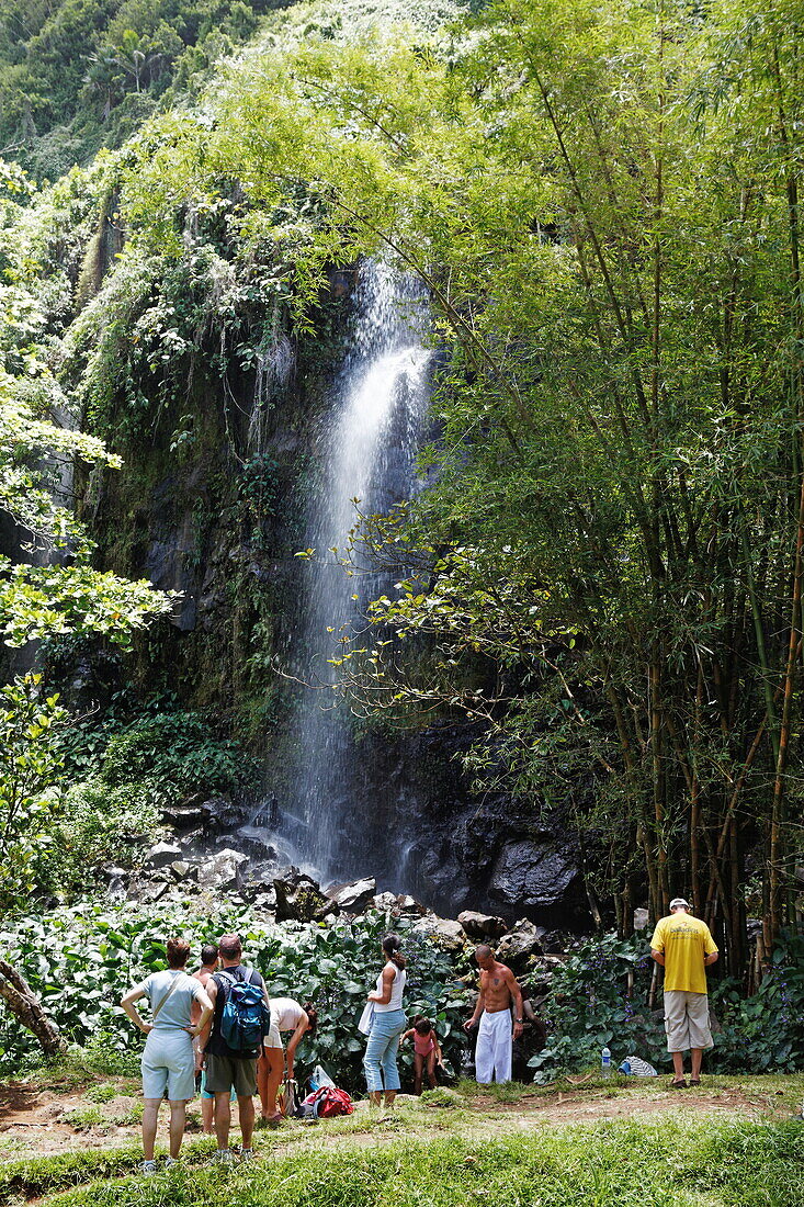 People in front of a waterfall at Anse des Cascade in Bois-Blanc, La Reunion, Indian Ocean