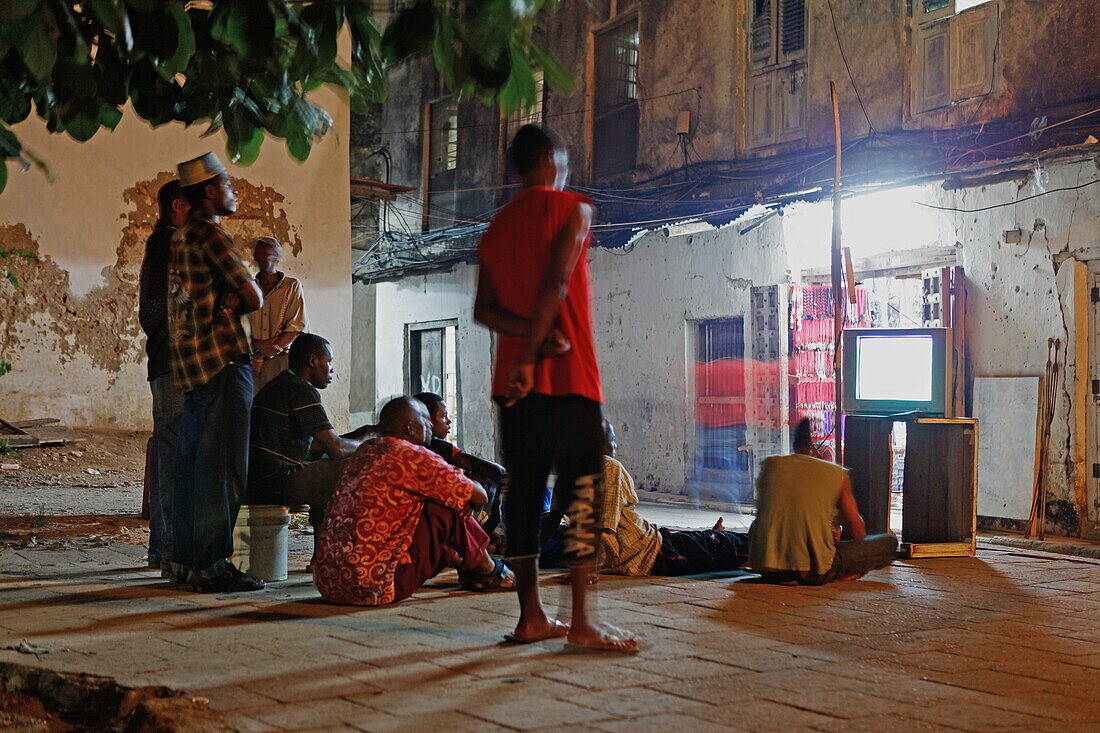 Local people watching TV in an alley of Stonetown, Zanzibar City, Zanzibar, Tanzania, Africa