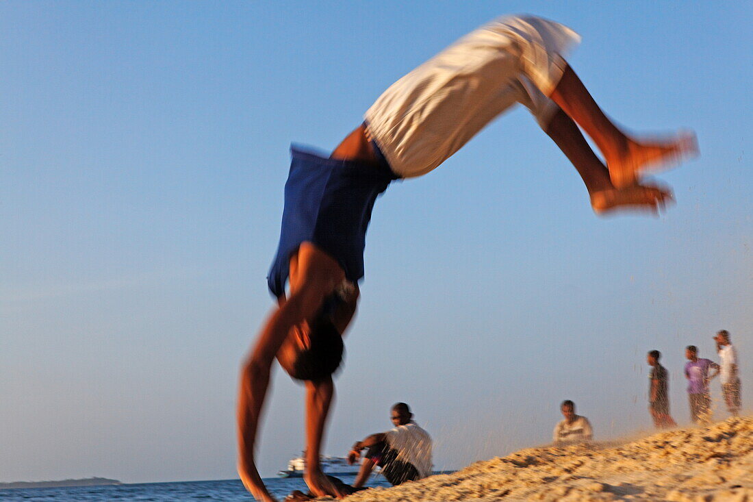 Junge macht Salto am Stadtstrand von Stonetown, Sansibar City, Sansibar, Tansania, Afrika