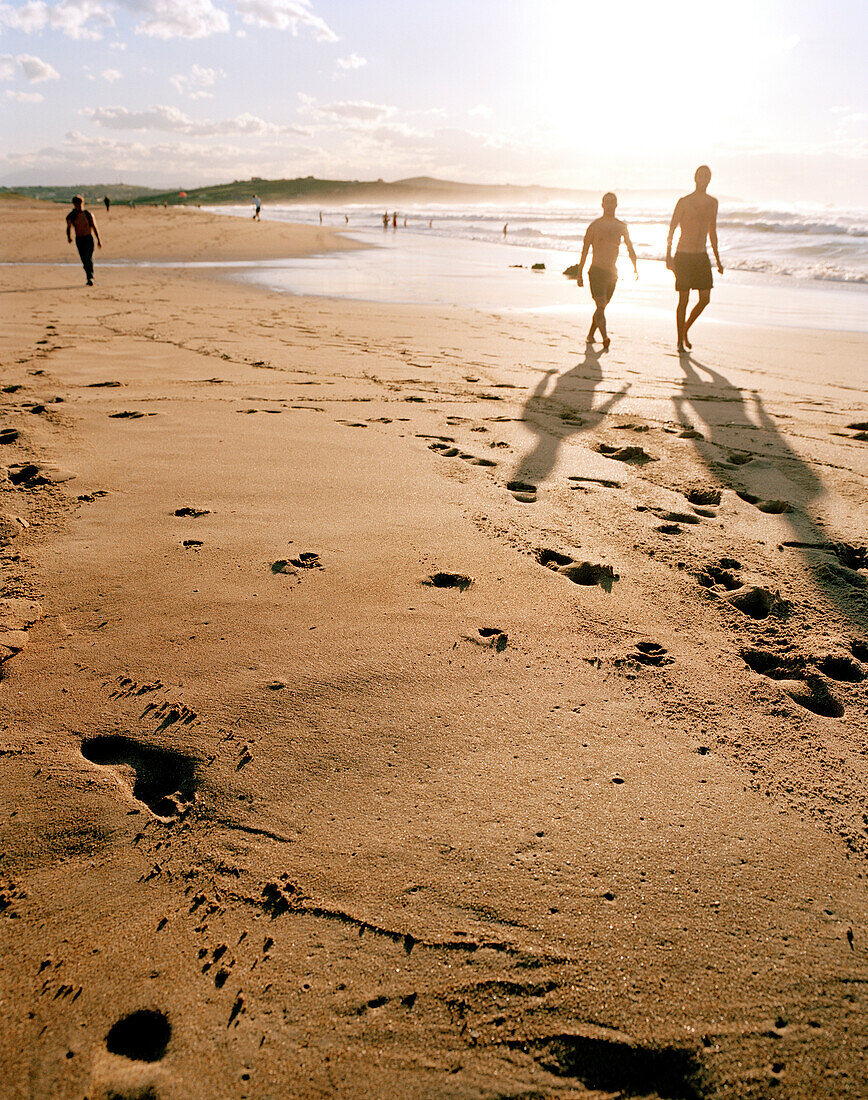 People walking along the beach at sunset, Playa de Valdearenas, west of Santander, Cantabria, Spain