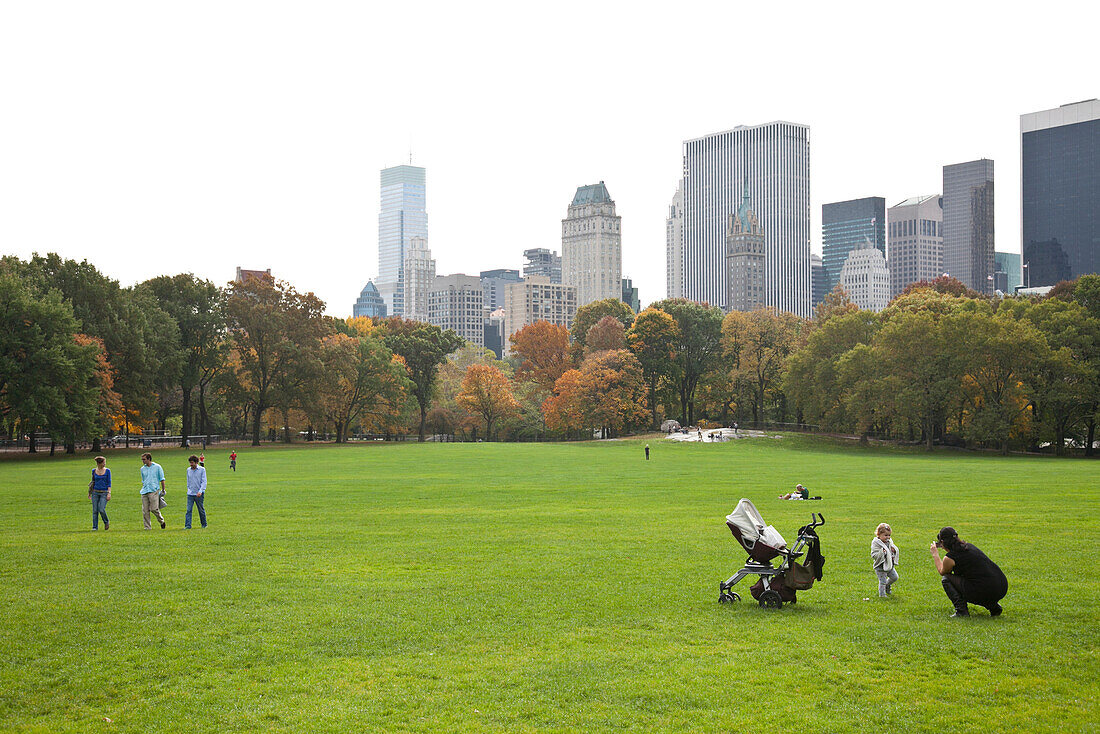 Central Park im Herbst, Mutter mit Kind Kinderwagen, Wiese, Hochhäuser, Park Avenue, Manhattan, New York City, Vereinigte Staaten von Amerika, USA