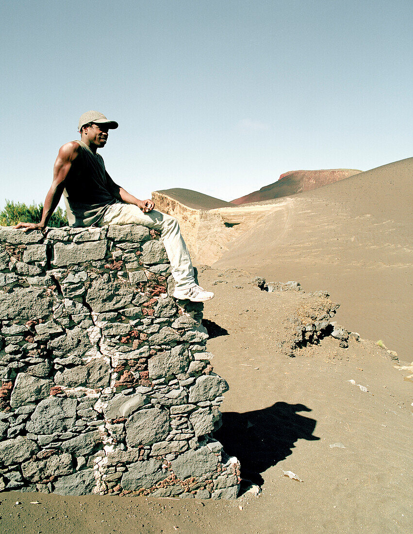 Labourer sitting on a wall, former village has been buried by a vulcanic eruption in 1958, Vulcao dos Capelinhos, Faial island, Azores, Portugal