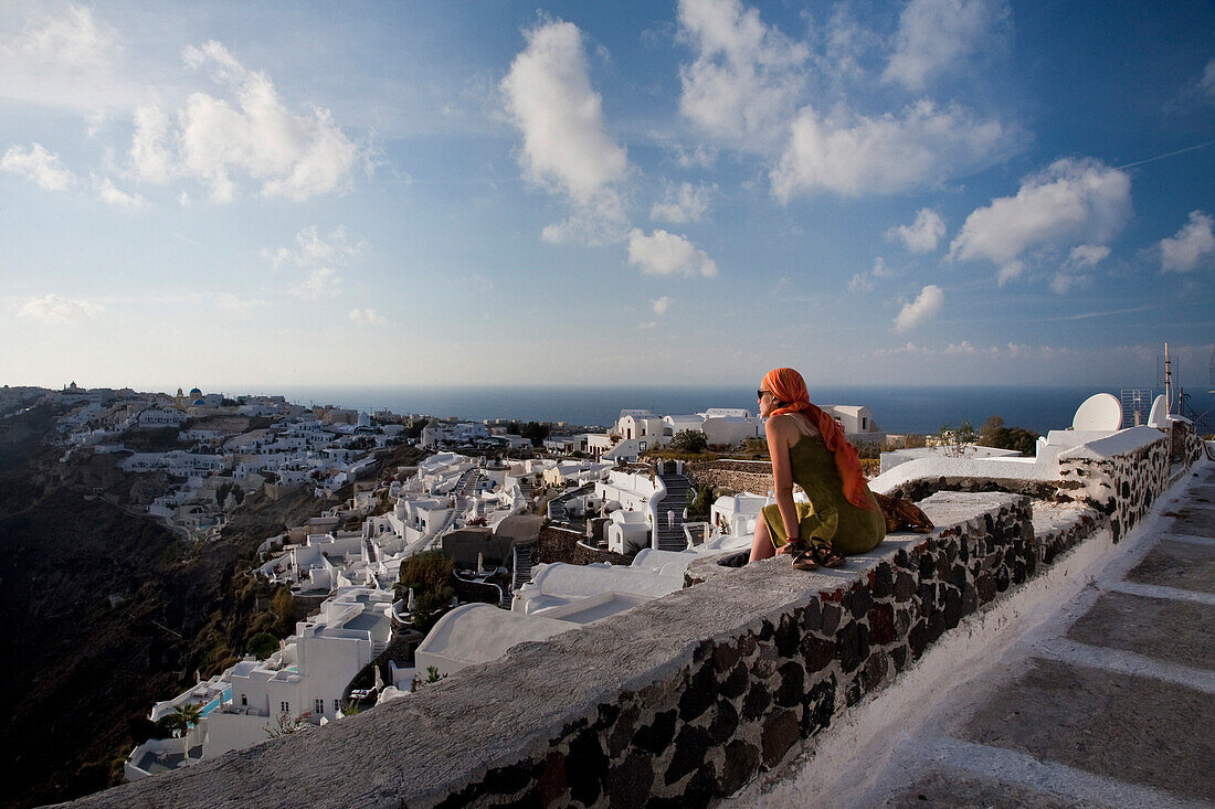 Woman on wall overlooking town, Oia, Santorini Island, Greek Islands