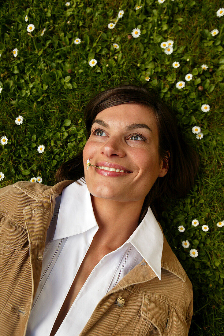 Mid adult woman lying in daisy meadow