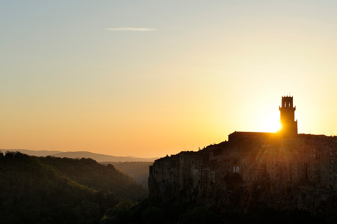 Sonne geht hinter Kirchturm von Pitigliano unter, Pitigliano, Toskana, Italien