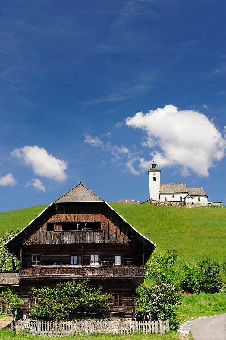 Altes Kärntner Holzhaus mit Kirche von Arriach, Mittelpunkt von Kärnten, Arriach, Kärnten, Österreich, Europa