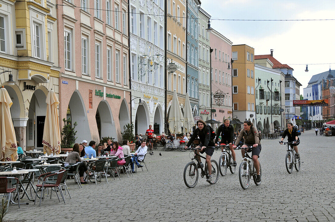 Vier Radfahrer fahren über Max-Joseph-Platz, Rosenheim, Bayern, Deutschland