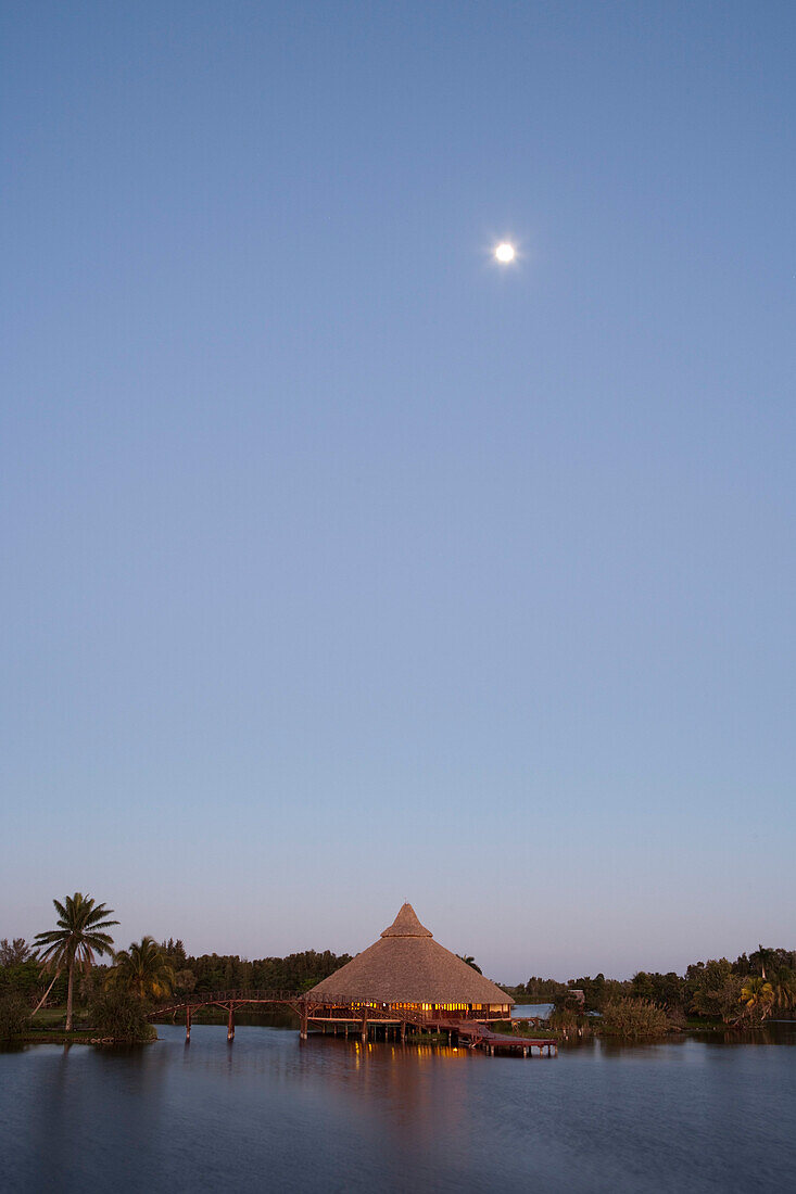 Moon above restaurant at Villa Guama hotel on the shores of Laguna del Tesoro (Treasure Lake) at dusk, Guama, Matanzas, Cuba