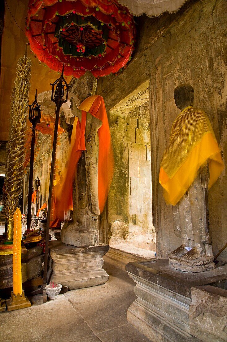 Cambodia, Angkor, Angkor Wat Buddhist statues colourfully decerated within the dramatic remains of Angkor Wat