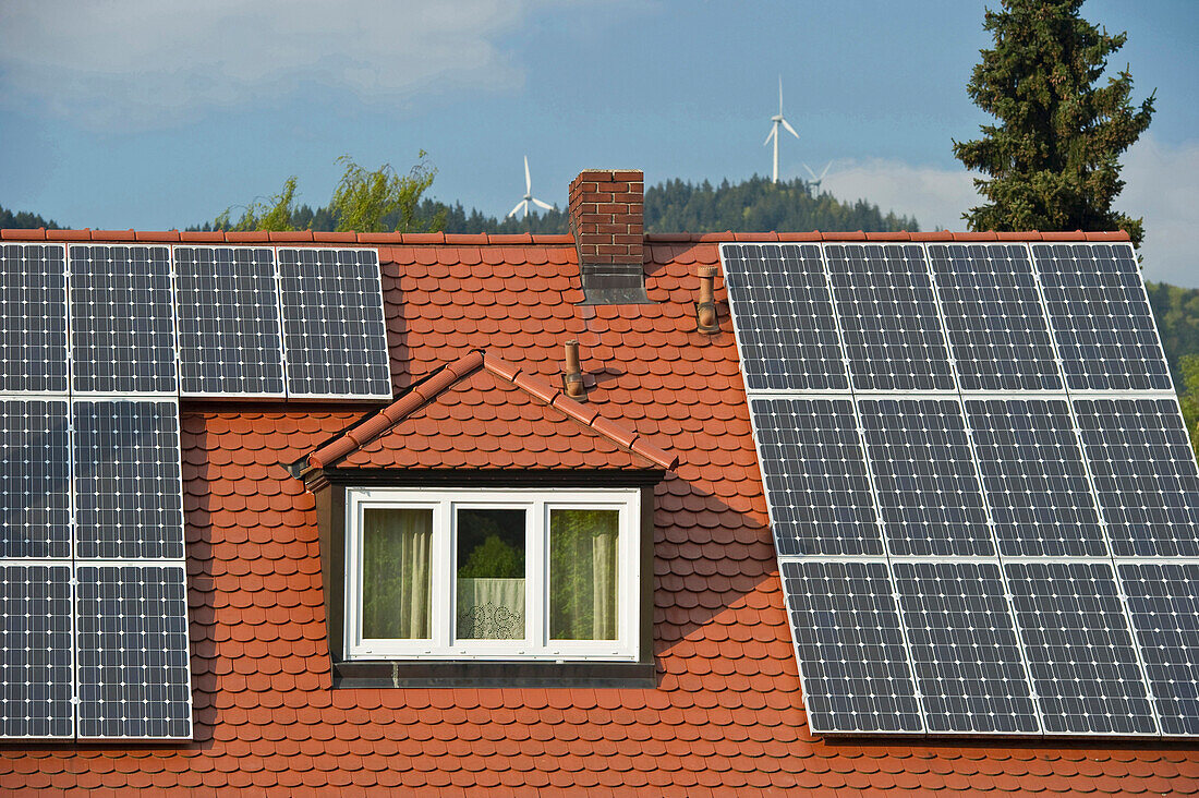 Solar installations on the roof of a private home and wind turbines in the background, Freiburg im Breisgau, Baden-Wuerttemberg, Germany, Europe