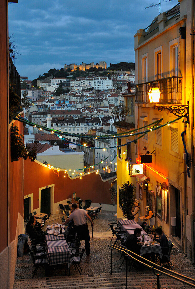 Sidewalk restaurant in the evening, Castle of Sao Jorge in background, Lisbon, Portugal