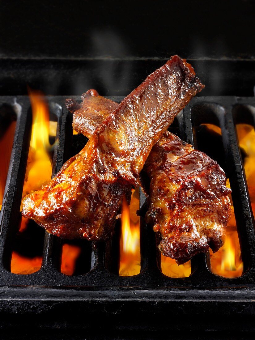 BBQ spare ribs being cooked over open flames.