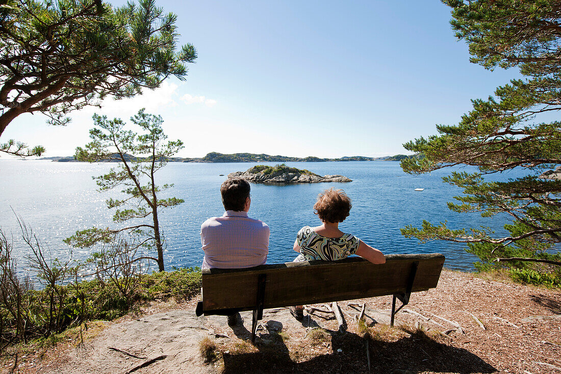 Älteres Paar sitzt auf einer Bank und blickt aufs Meer, Küste bei Mandal, Vest-Agder, Süd Norwegen, Skandinavien, Europa