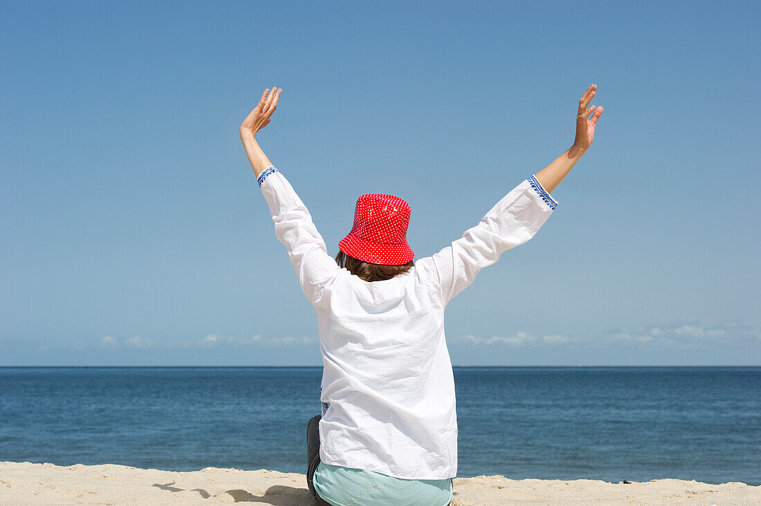 Frau mit Hut streckt sich am Strand, List, Sylt, Schleswig-Holstein, Deutschland