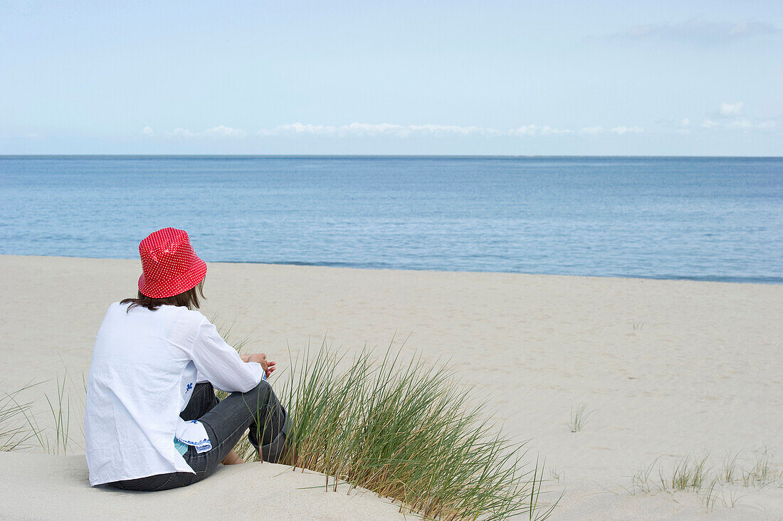 Frau mit Hut sitzt am Strand, List, Sylt, Schleswig-Holstein, Deutschland