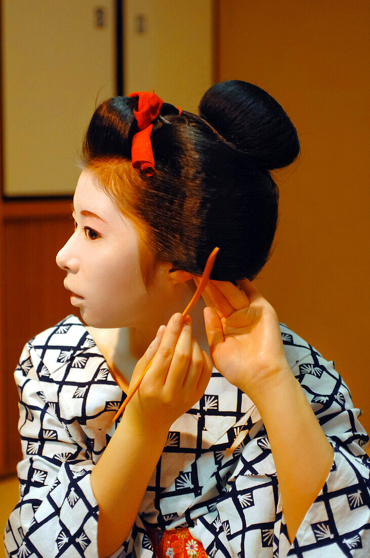 The Maiko's (Apprentice Geisha) Traditional Hairdo. a Maiko Arranging Her Chignon in the Form of a Peach (Wareshinobu) Adorned with Silk Ribbons (Kanoko) with a Comb (Kushi) Made of Boxwood, Gion District, Kyoto, Japan, Asia