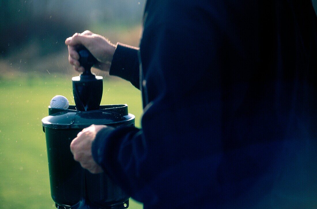 Golfer using a ball washer on golf course to clean golf ball