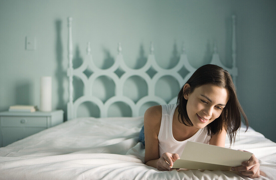 Woman lying on bed reading letter