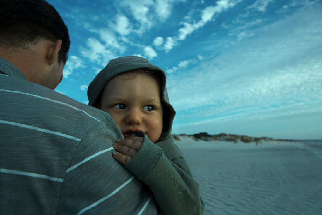 Man holding baby on beach, cropped