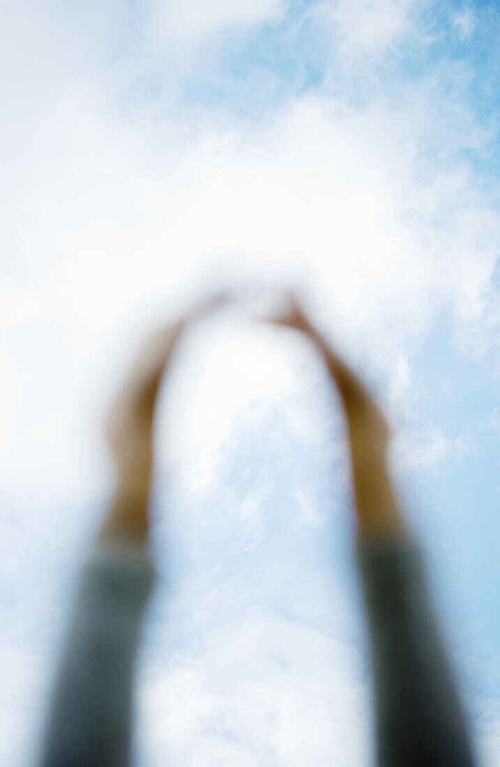 Arms reaching for sky, focus on sky in background