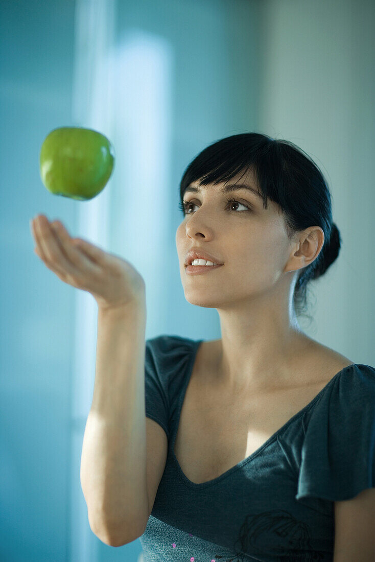 Apple floating in air above woman's hand