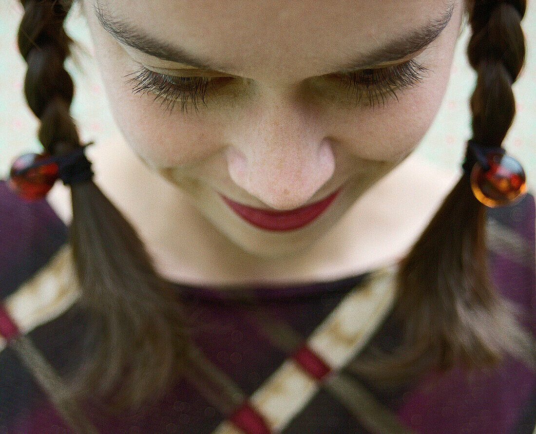 Young woman with pigtails looking down, close-up