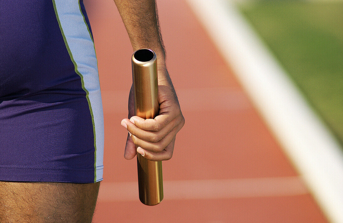 Athlete holding relay baton, partial view, close-up