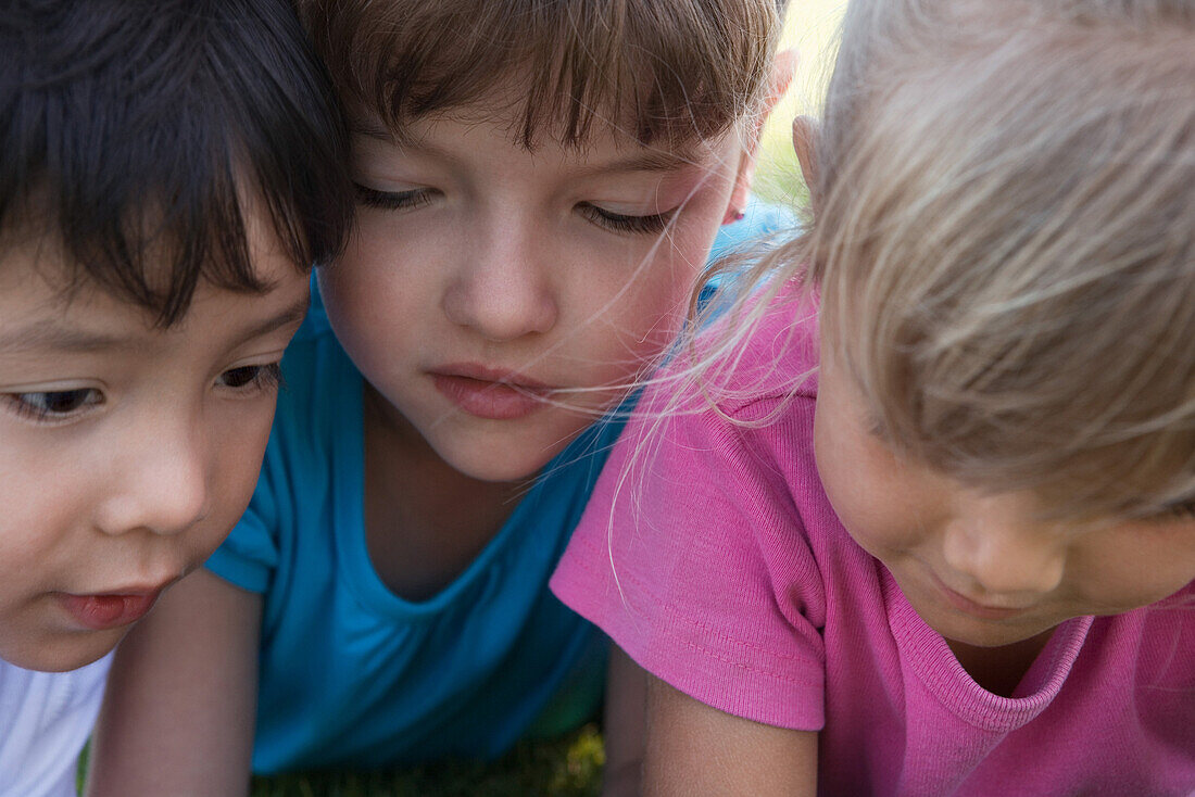 Three children with heads close together, cropped
