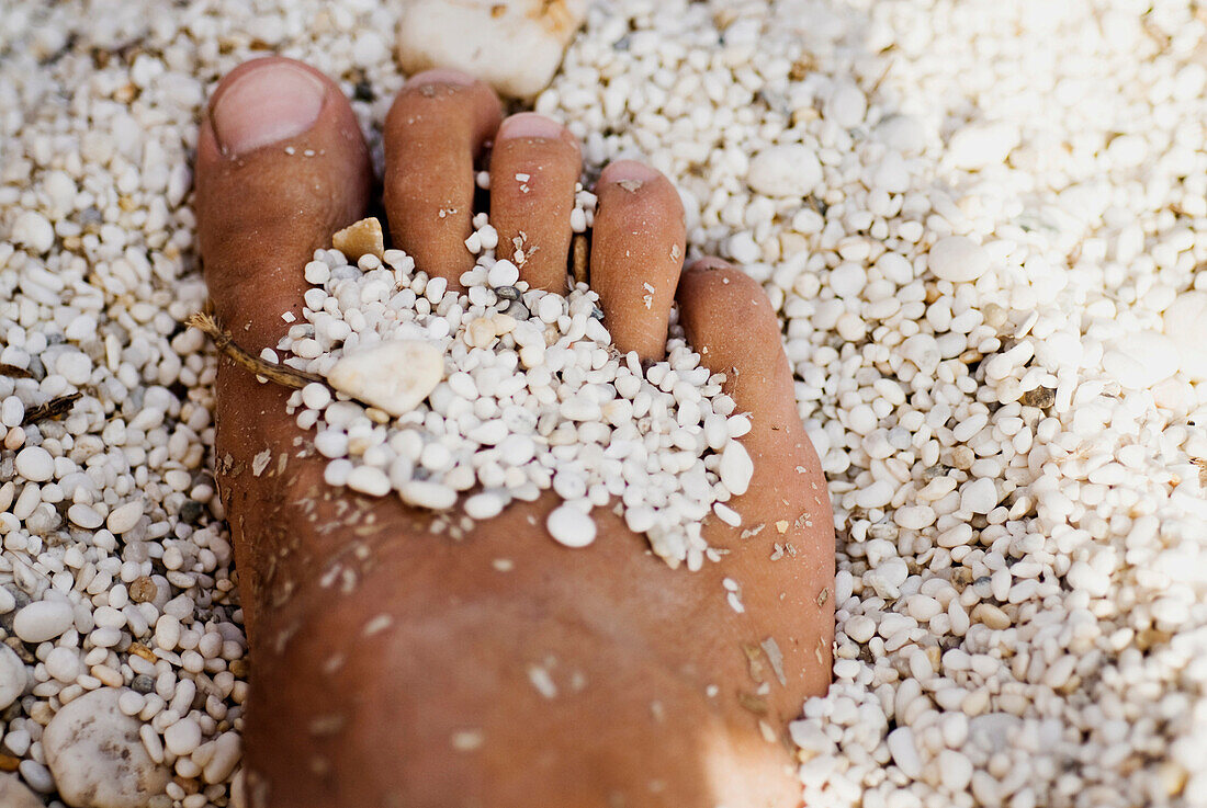 Foot With Small White Rocks at the Beach