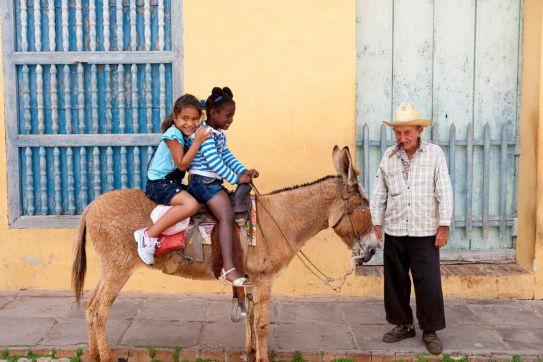 Kinder sitzen auf Esel an der Plaza Mayor in der Altstadt von Trinidad, Provinz Sancti Spiritus, Kuba, Karibik
