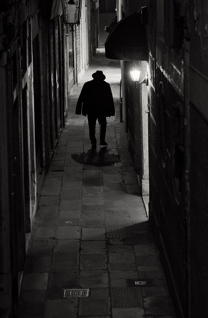 One man at night in Alley, Venice, Italy