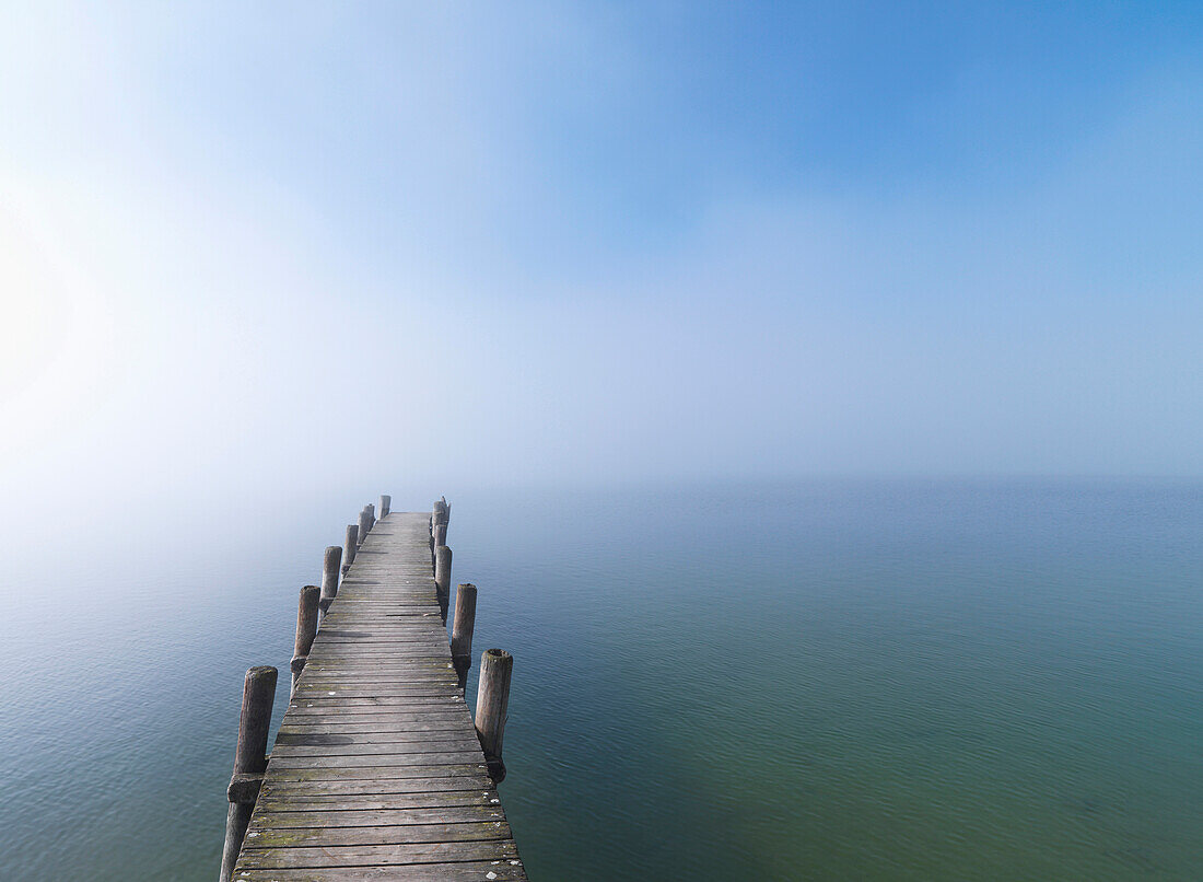 Wooden jetty in fog at lake Chiemsee, Frauenchiemsee, Chiemgau, Bavaria, Germany
