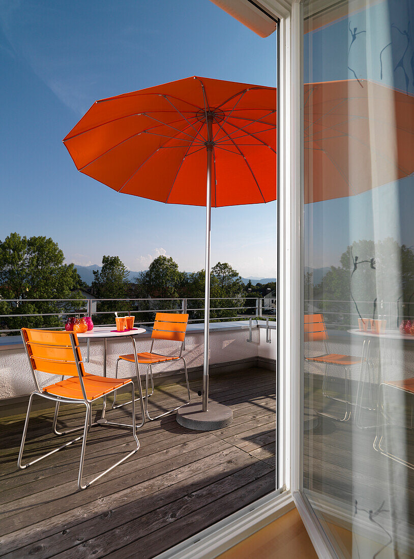 Balkon mit orangen Gartenmöbeln und rotem Sonnenschirm, Kolbermoor, Bayern, Deutschland