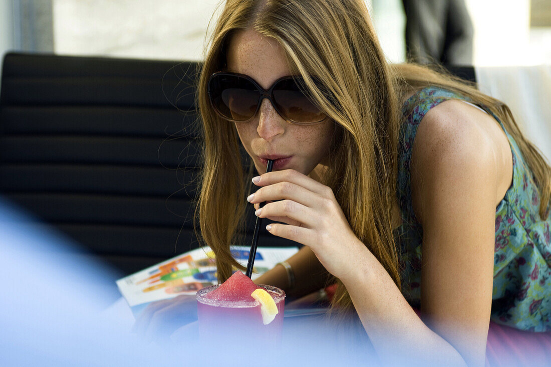 Young woman drinking frozen drink with straw