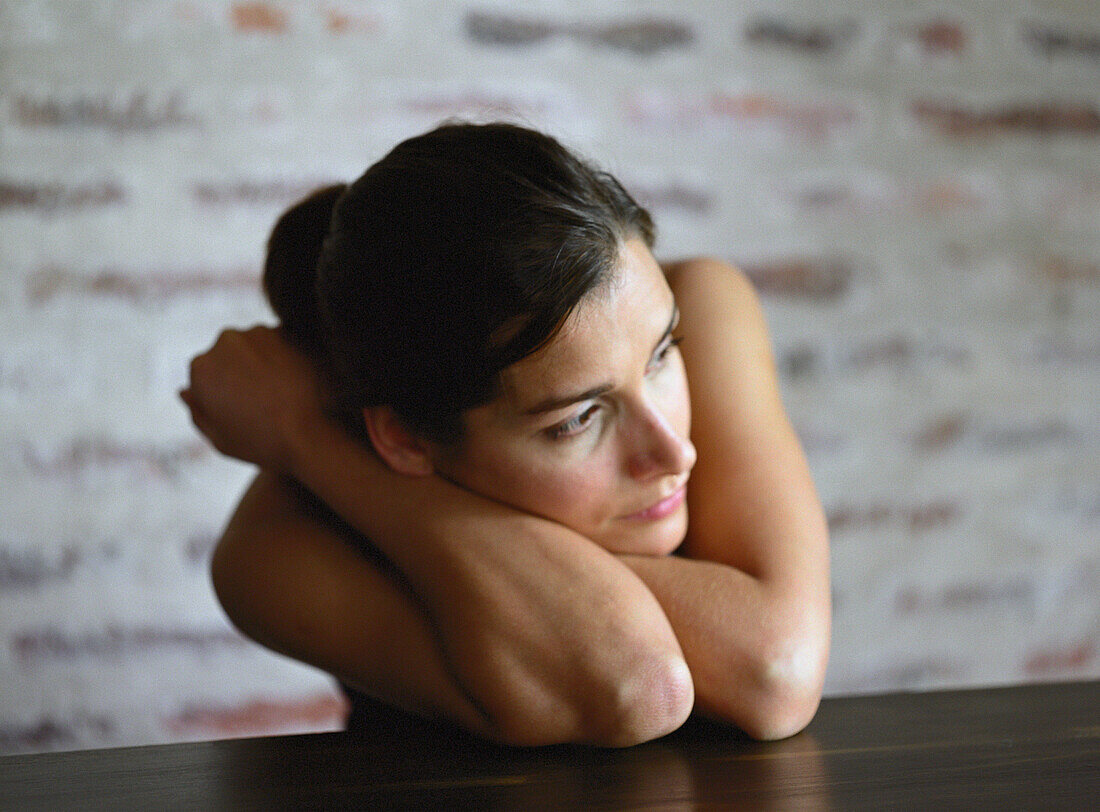 Young woman leaning on table, looking away