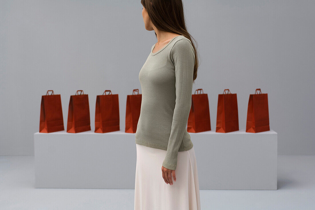Woman looking over shoulder at row of shopping bags