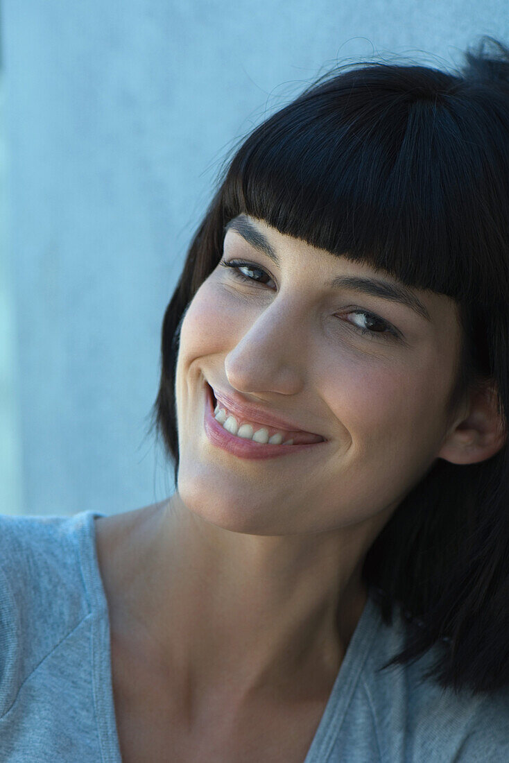 Young woman, leaning head against wall, smiling